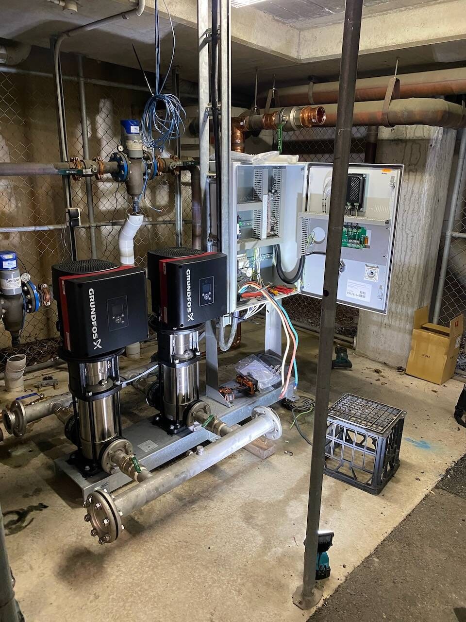 Twin booster pumps and control panels in a plant room