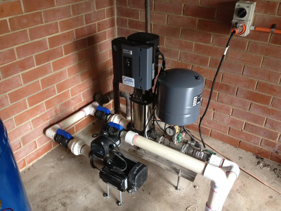 Grundfos booster pump and pressure tank installed against a brick wall