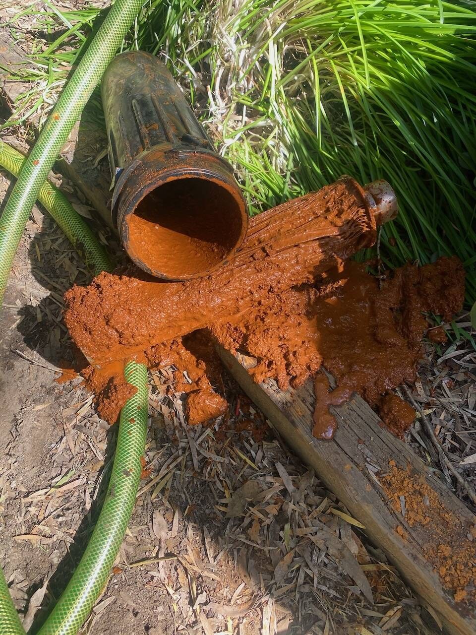 Orange iron sludge flushing out of a pipe