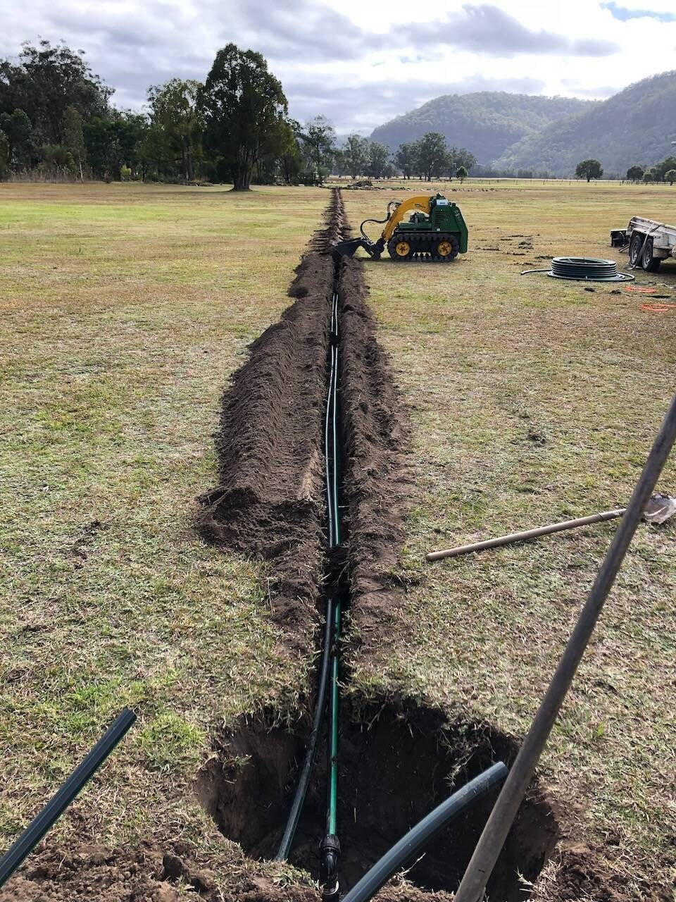 A long mainline trench running across a paddock