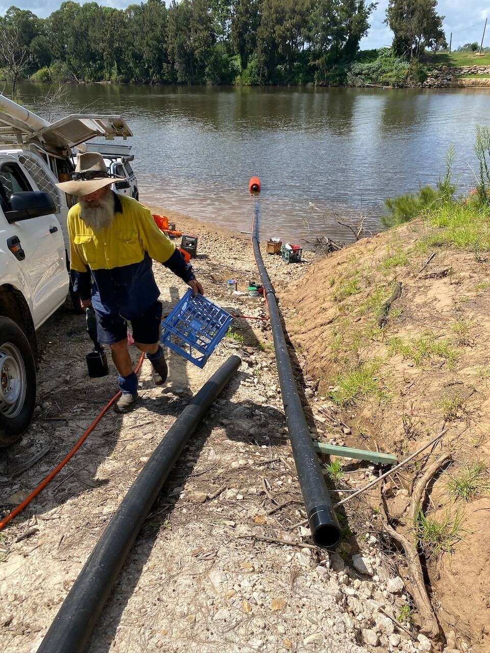 Laying black poly intake pipe down a riverbank to a float