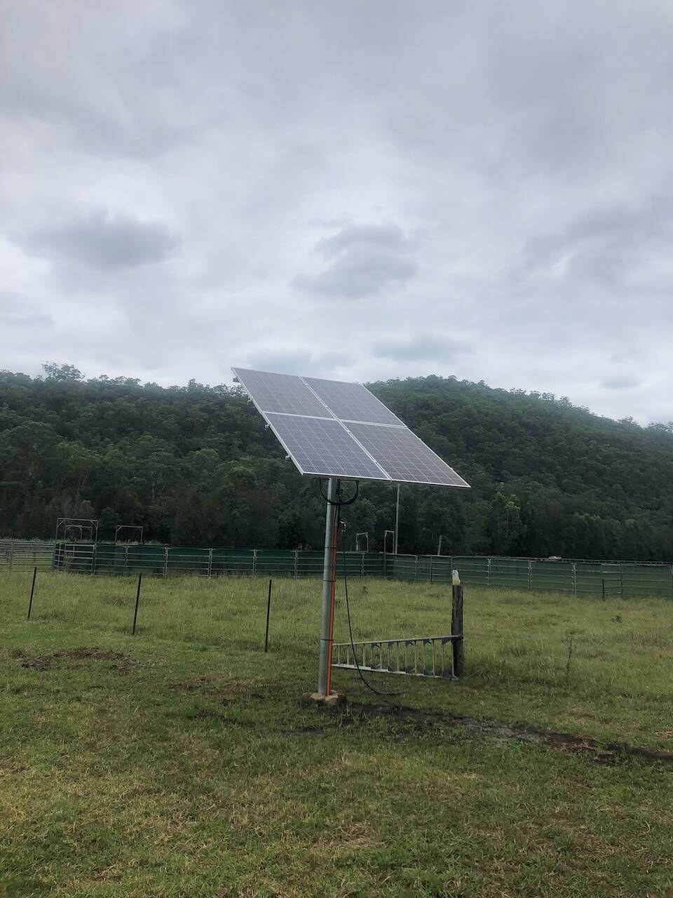 Pole-mounted solar panel in a green paddock