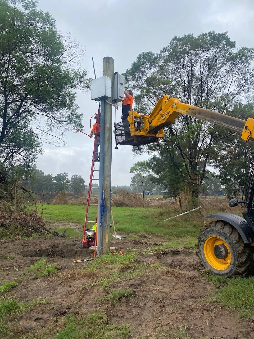 Telehandler lifting a worker up to a pole-mounted cabinet