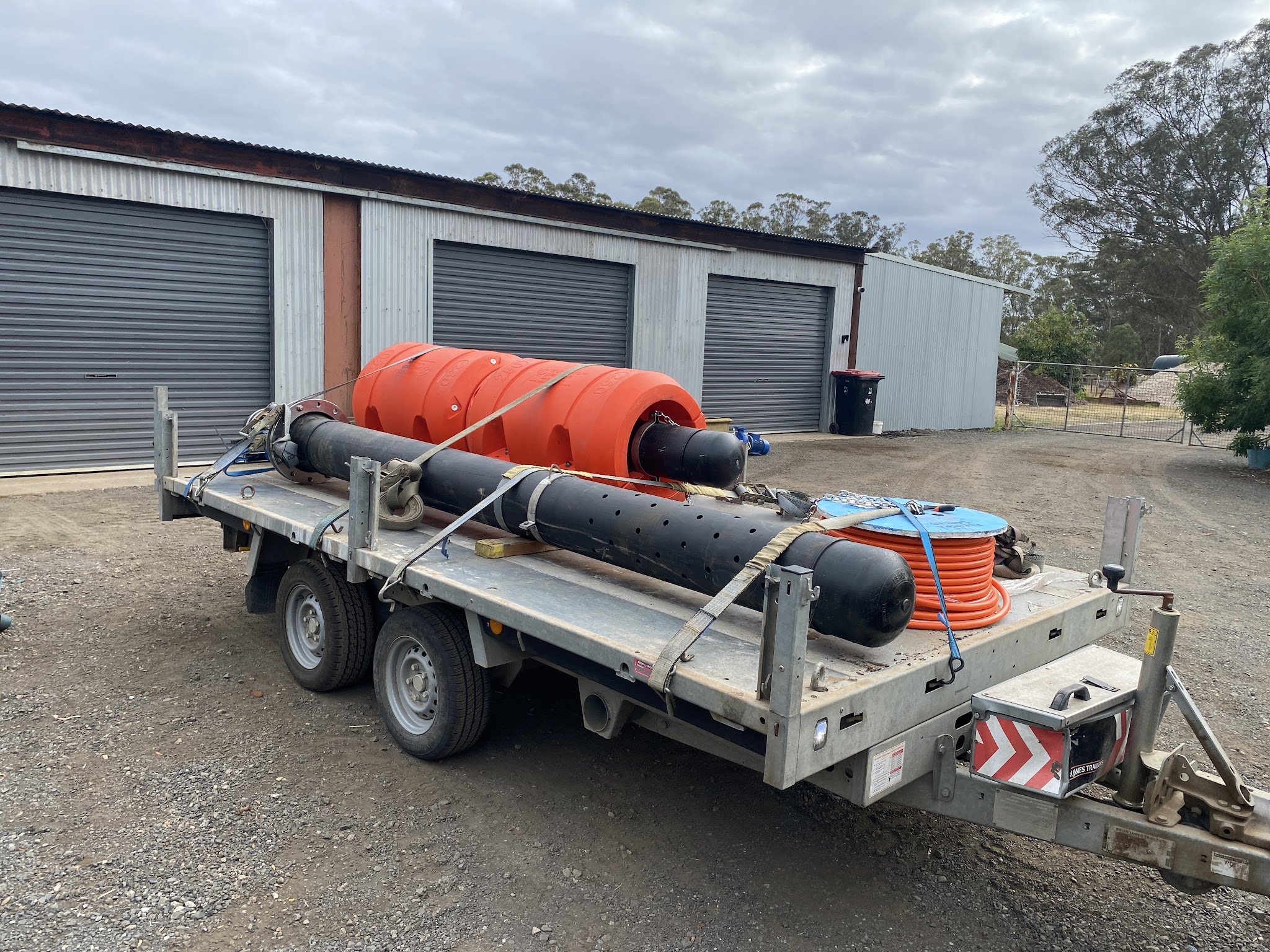 Float-mounted river pump, float and cable loaded on a trailer outside the workshop